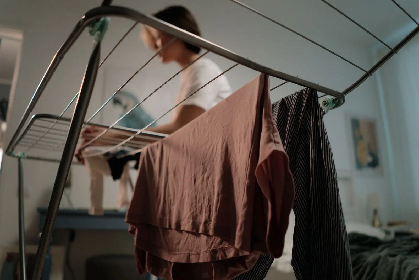A person standing behind an indoor rack with a brown garment hanging in front