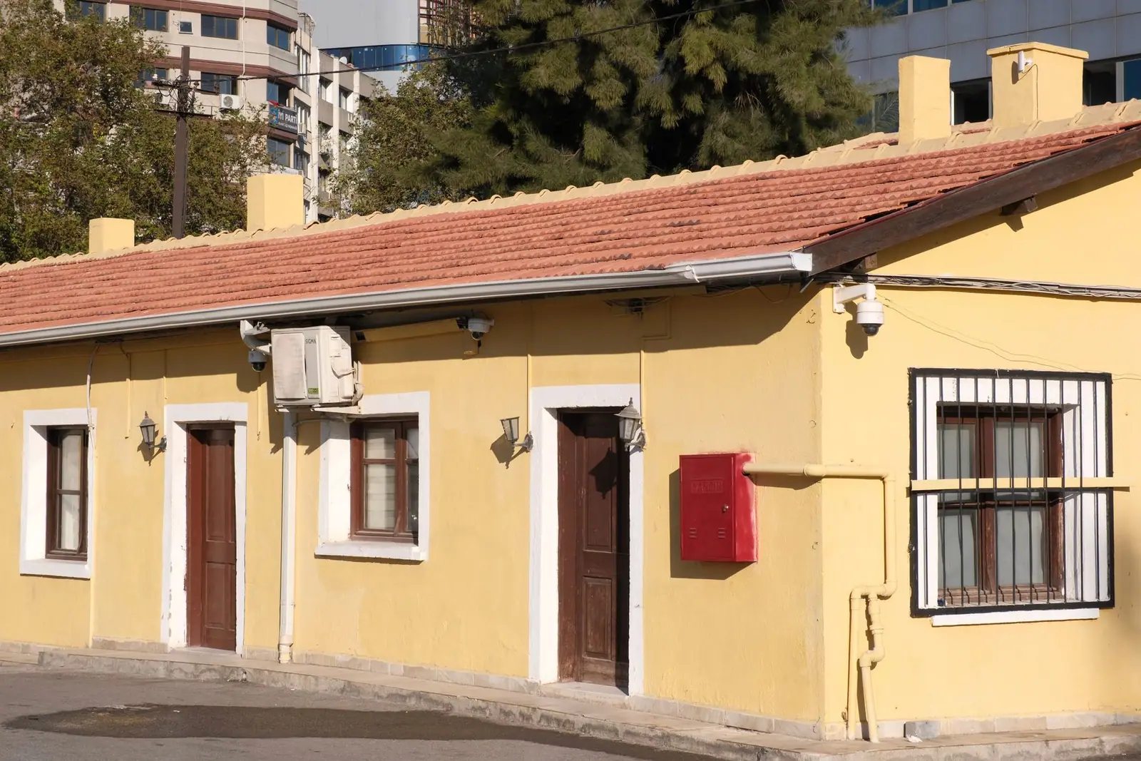 A yellow house on a sunny street with a red mailbox by the door
