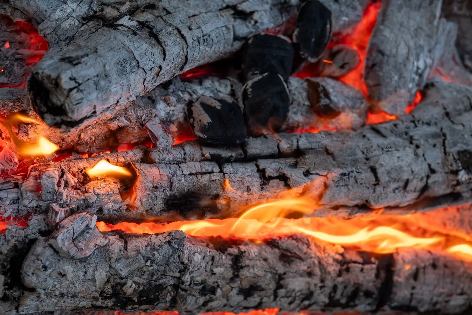 Glowing embers beneath a burning log