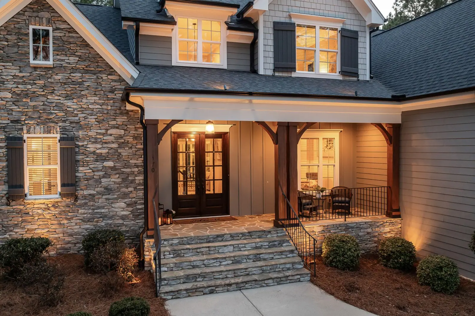 The lit front porch of a house with a stone facade at dusk