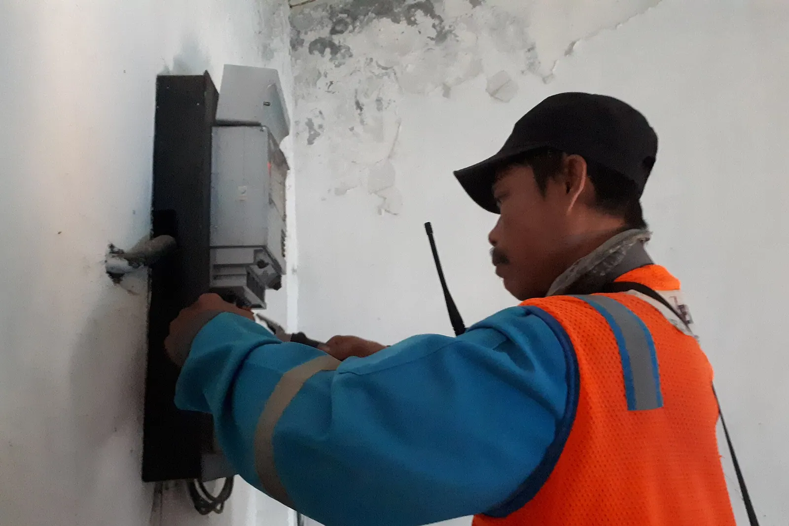 A technician working on a wall-mounted electricity meter