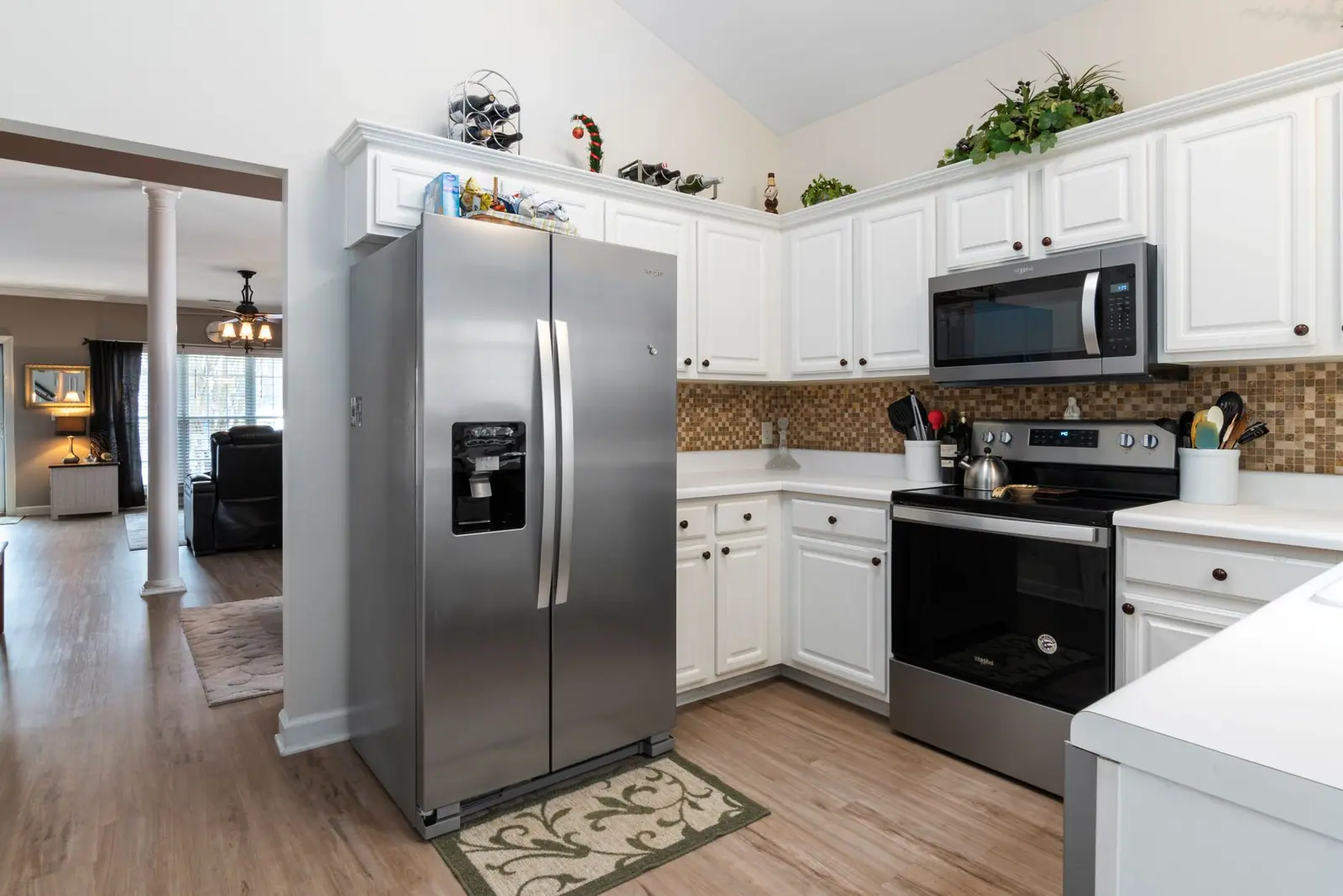 A stainless steel side-by-side refrigerator beside white kitchen cabinets and a stove