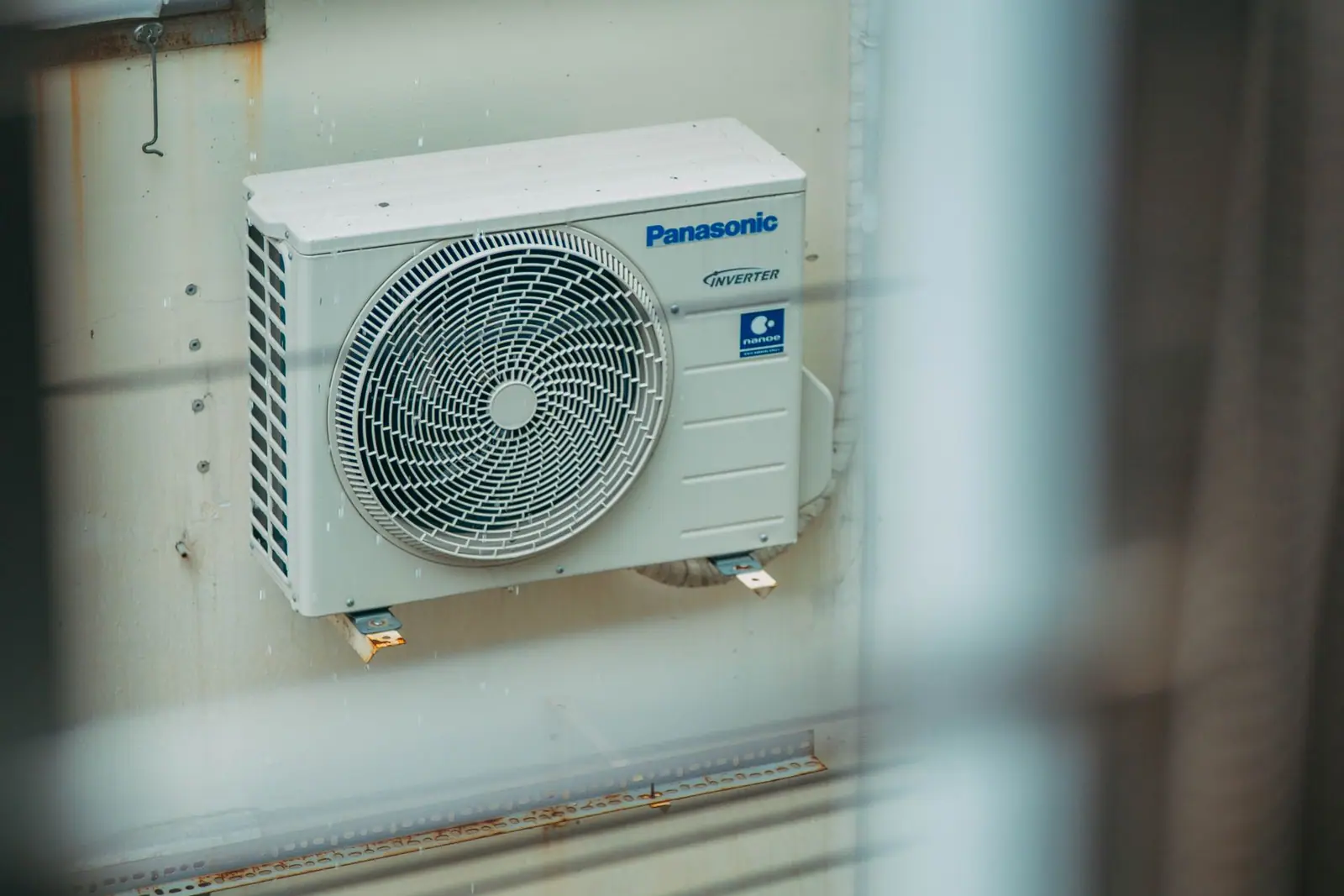An outdoor heat pump unit mounted on the wall of a building