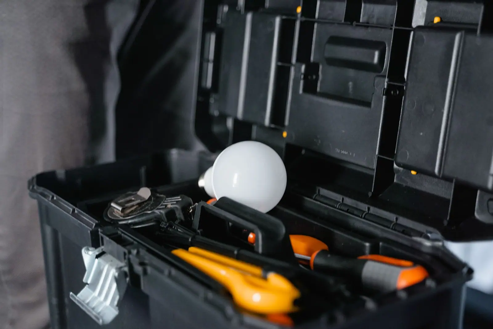 An open black toolbox containing hand tools and a light bulb