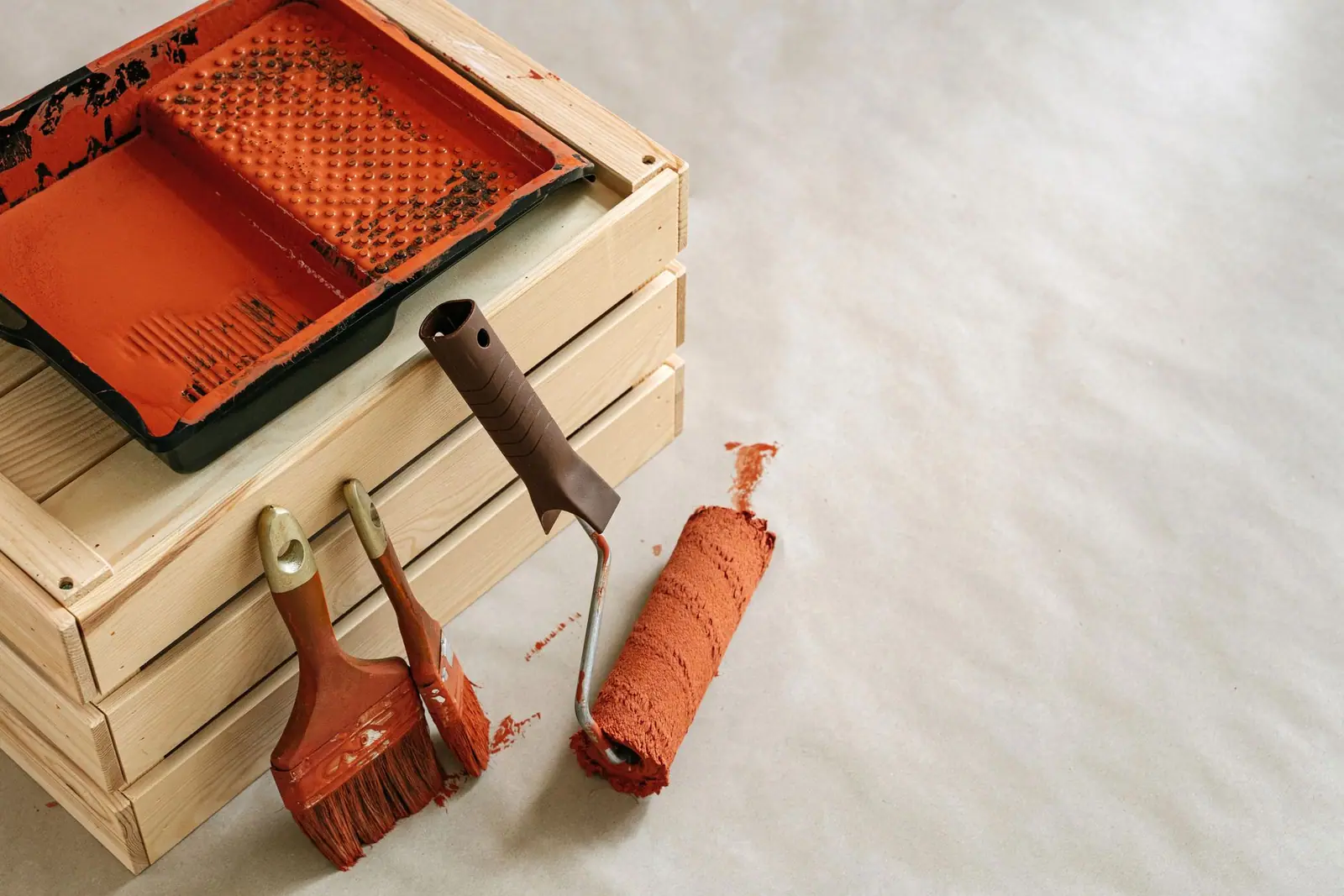 A paint tray, brush and roller resting on a crate