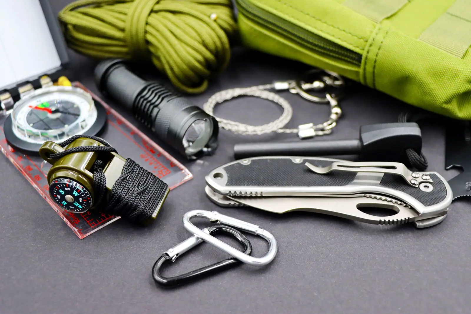 A torch, compass, multi-tool and cord laid out on a surface