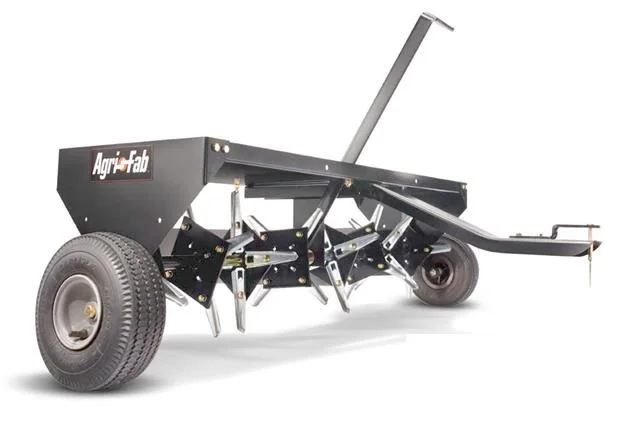 A gray tow-behind plug aerator with wheels and a row of hollow soil-pulling tines