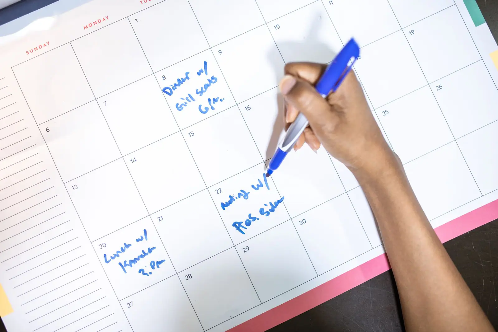 A hand writing on a monthly wall calendar