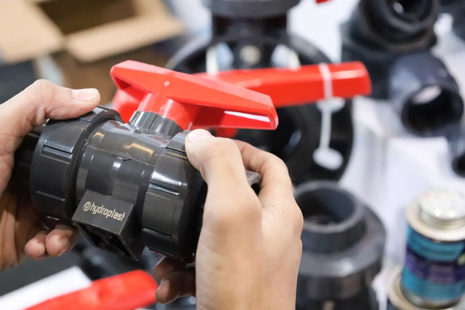 Gloved hands fitting a PVC ball valve to pipework