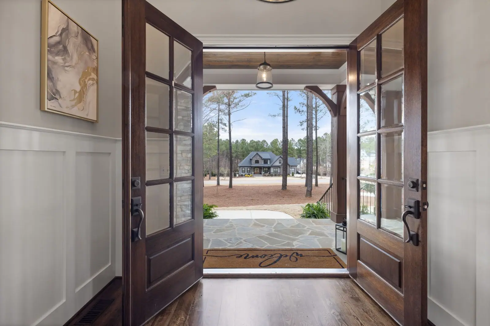 Open wooden double doors viewed from inside a house toward a front path and lawn