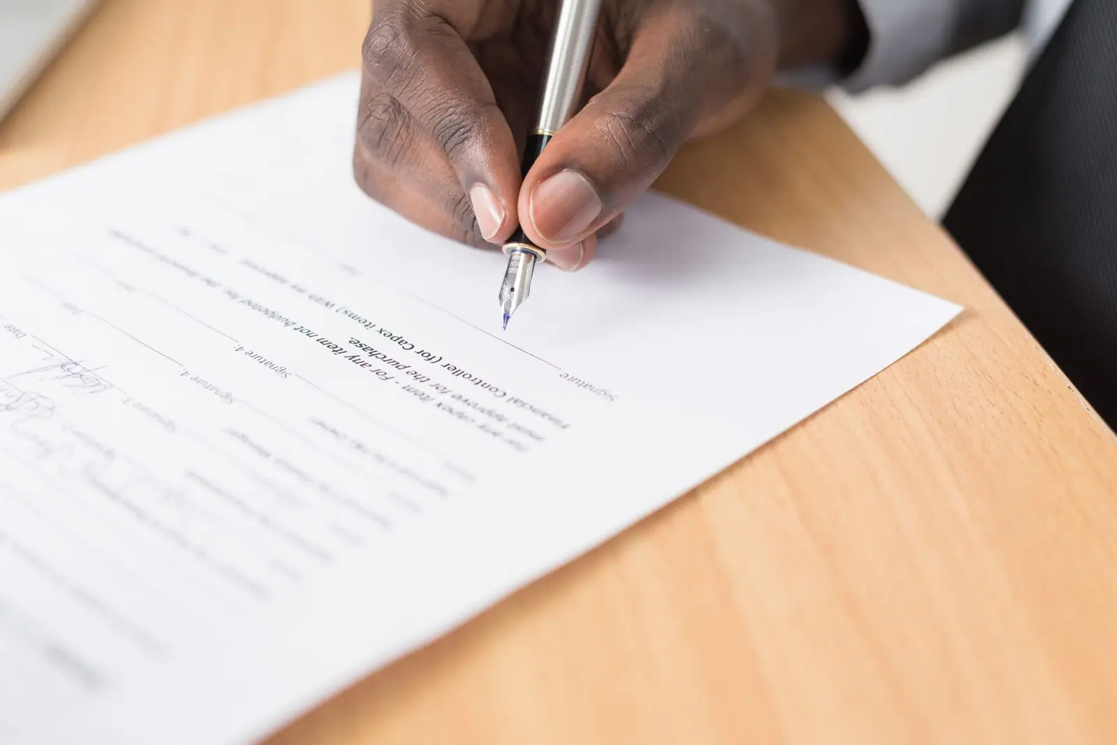 A hand signing a printed document on a table