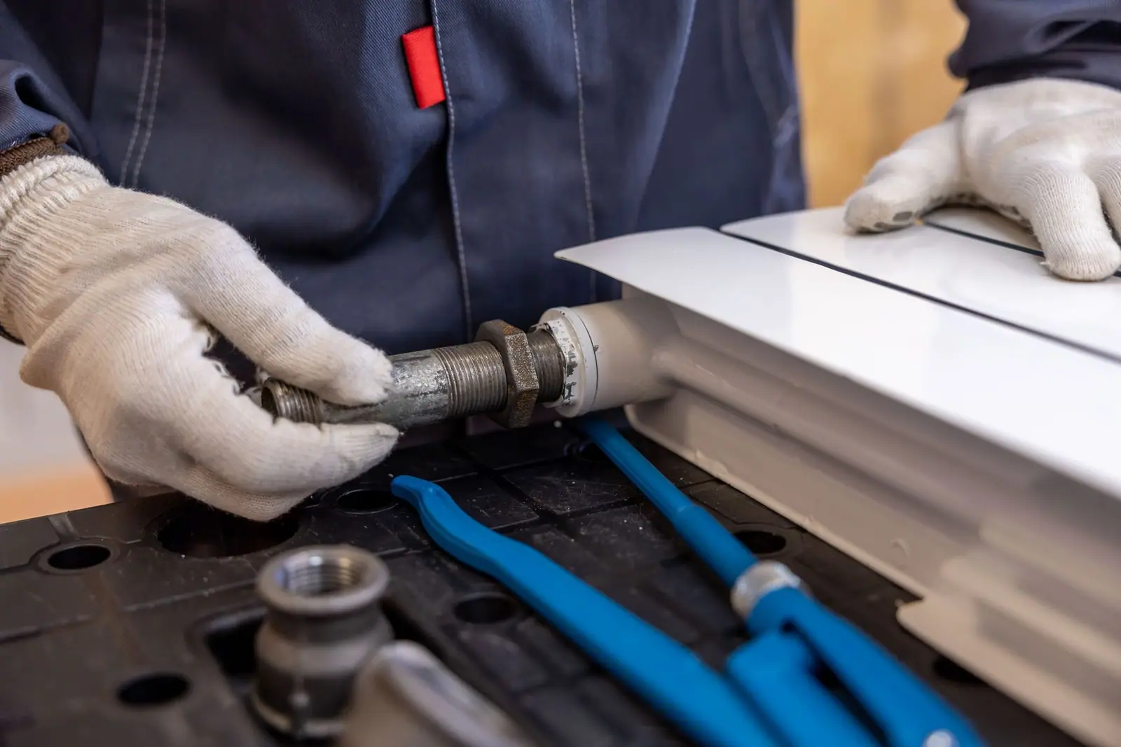 Gloved hands fitting white PVC pipework