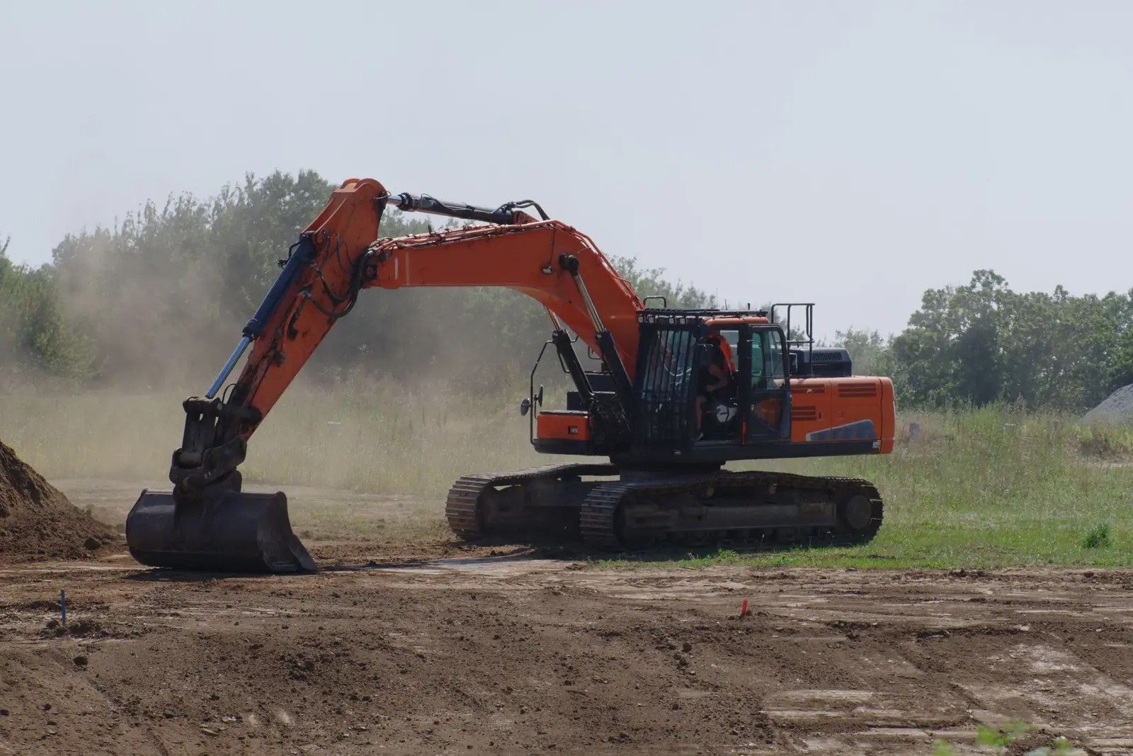 An excavator levelling bare earth at an outdoor site