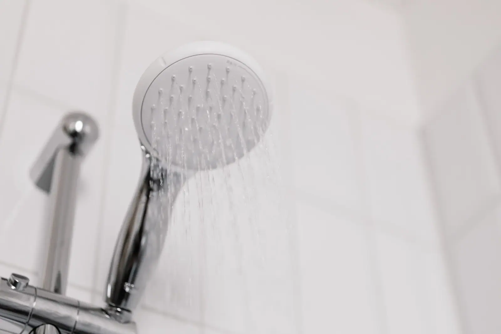 A round white-faced handheld showerhead on a chrome hose