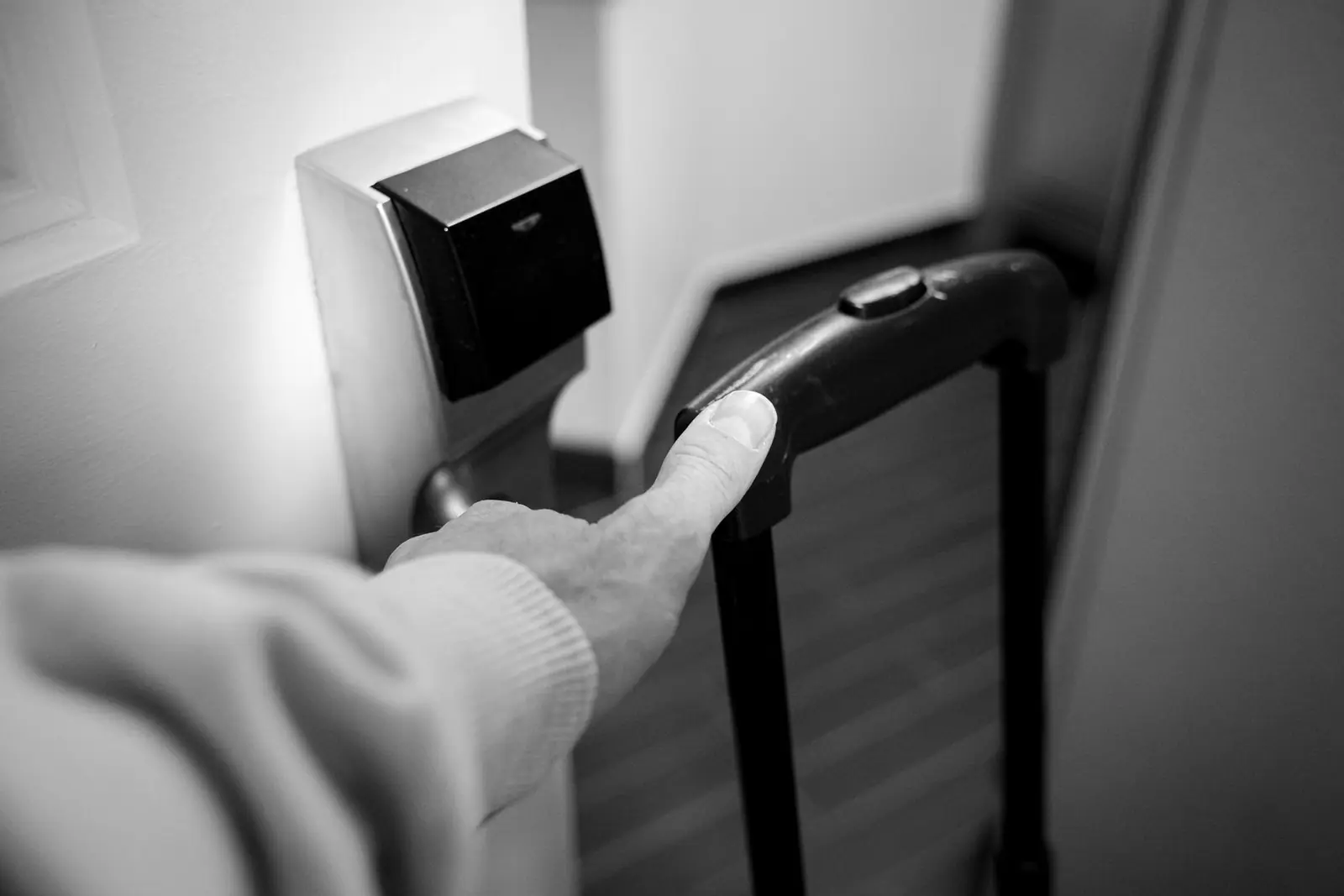 A hand opening a hotel room door with an electronic lock
