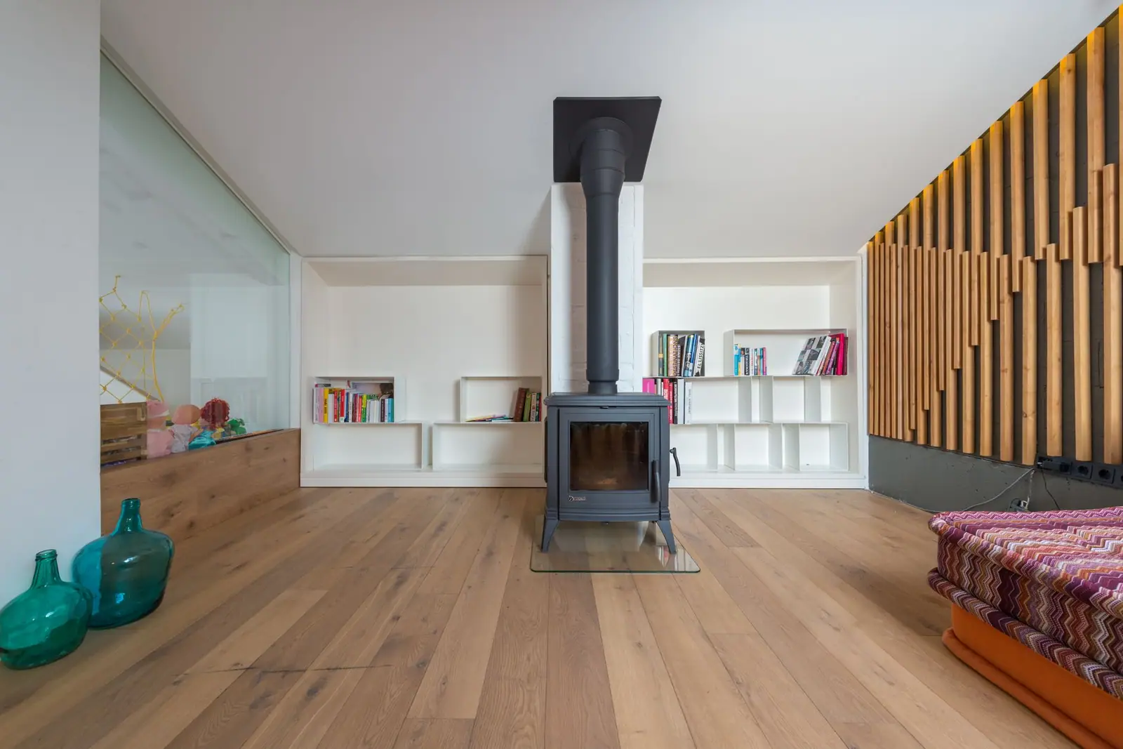 A freestanding stove and metal flue in a bright room with wooden flooring