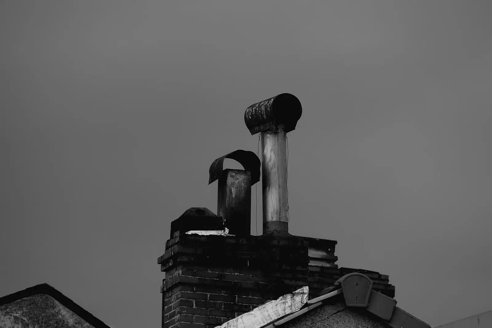 A chimney with a metal cowl against a grey sky