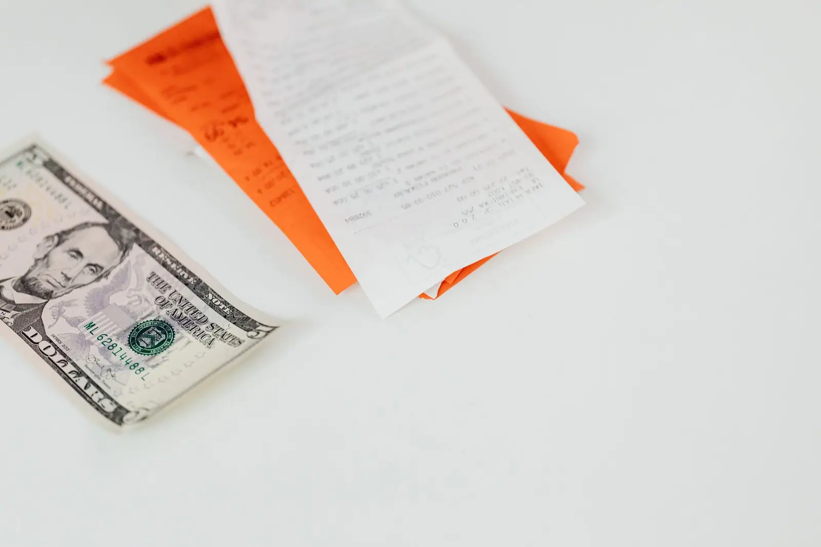 Paper receipts and a banknote on a white surface