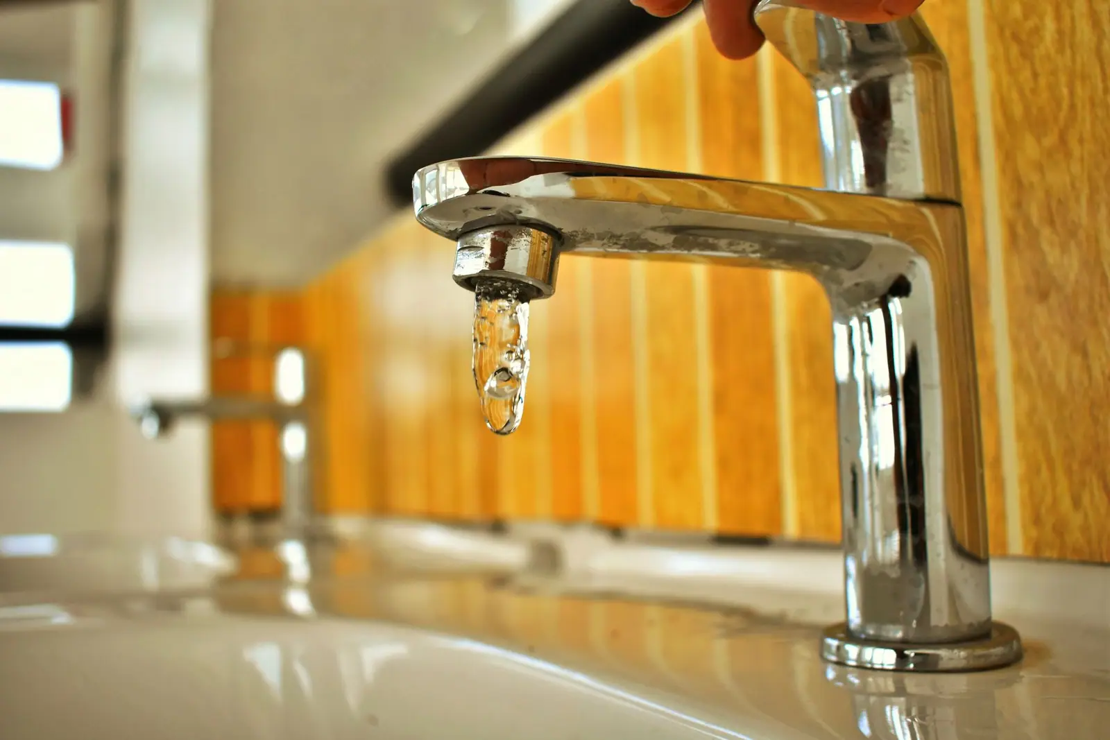 Water running from a metal faucet into a sink