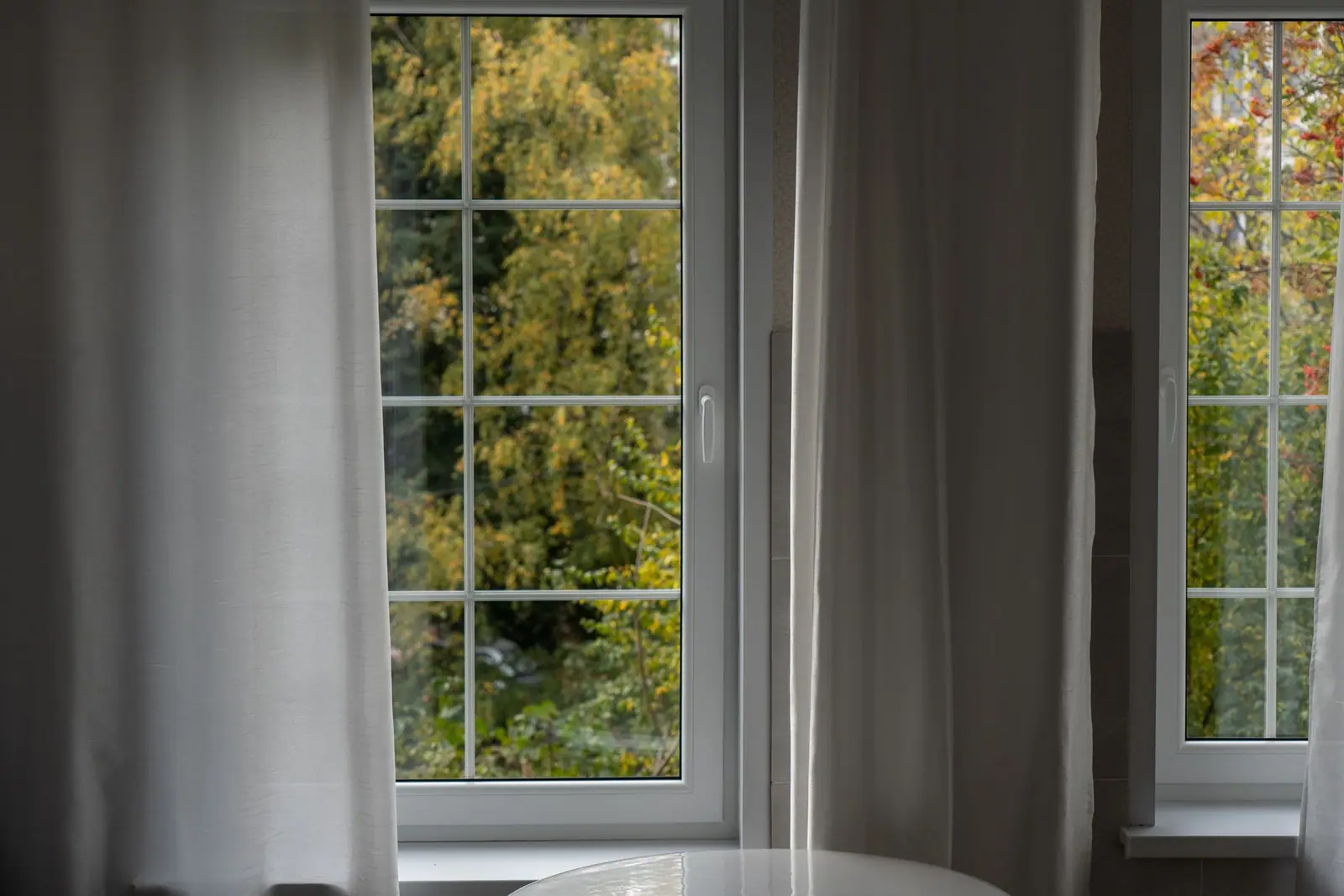 A white-framed window with divided panes beside curtains